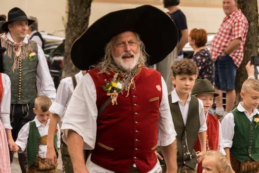 Villach, Austria - August 6, 2022: People enjoy the procession of 'Villacher Kirchtag', the largest traditional folk festival in Austria, after some years of cancellation due to Covid.