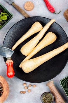 Raw parsnip roots on the kitchen table. Root vegetables. White root