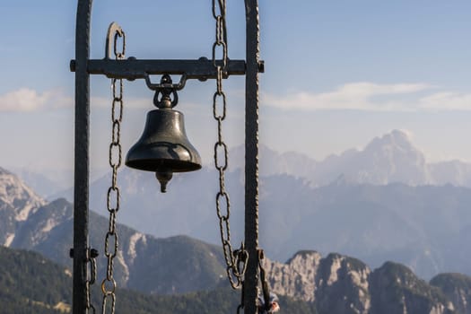 View from Mount Auernig to the Julian Alps with the summit bell in the front at a beautiful sunny autumn day