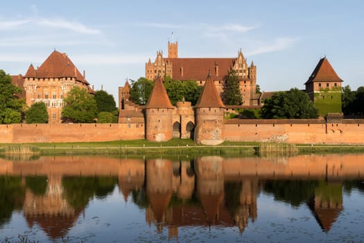 Beautiful view over the river to the worlds largest castle by area, the medieval Malbork Castle in Poland.