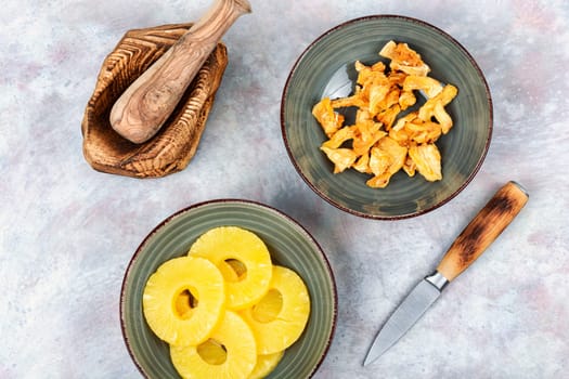 Dry and fresh pineapples in bowls. Candy pineapples, candied fruits. Fruit snack.