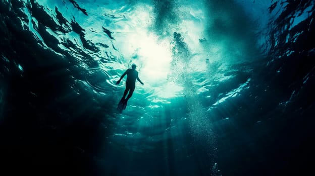 deep waters. A lone diver emerges towards the light from the depths of the ocean.