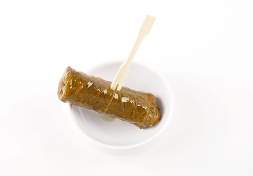 Stuffed vine leaves on wooden skewers and porcelain bowl on white background