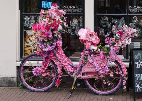 Amsterdam, Netherlands - April 21, 2023: Old bicycle decorated with pink flowers in De Wallen - called the red light district. It is famous for its entertainment character