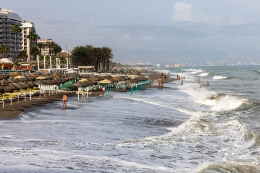 Torremolinos, Spain - September 14, 2023:  Foamy sea waves on the sandy beach of Bajondillo in Torremolinos, Malaga, Costa del Sol, Spain