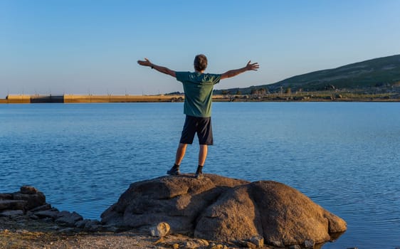 Man tourist standing overlooking at picturesque view of the Lake of Viriato, in Serra da Estrela, Portugal. View from behind