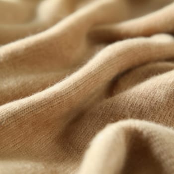 Close-up of beige cashmere wool fabric, highlighting texture and quality