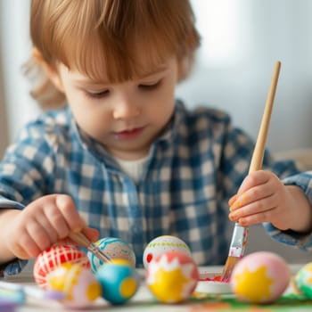 Cute child paints beautiful Easter eggs with a brush. Holiday traditions