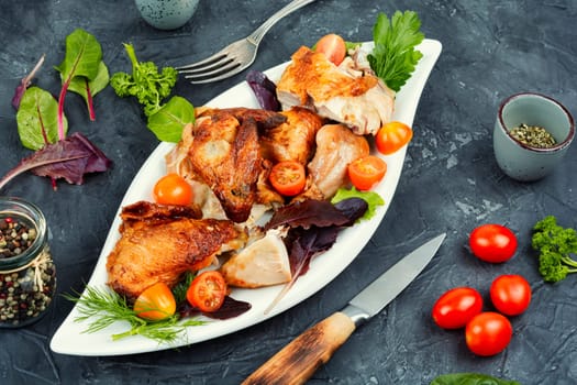 Sliced baked grilled chicken with cherry tomatoes on a plate.