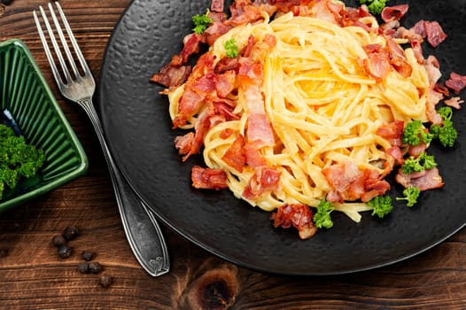 Pasta Carbonara with bacon and parmesan on a plate on old rustic wooden table. Italian pasta dish.