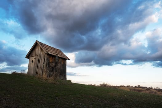 Dramatic image of old wooden hut with cloudy sky.
