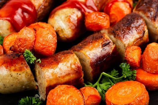Grilled or baked wurst sausages served with carrots and ketchup. BBQ roast Bratwurst meat sausages. Macro.