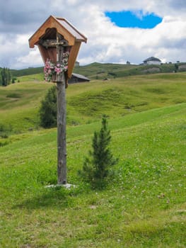 scenic view to a religious cross in the dolomites with hut in backgroud, Italy