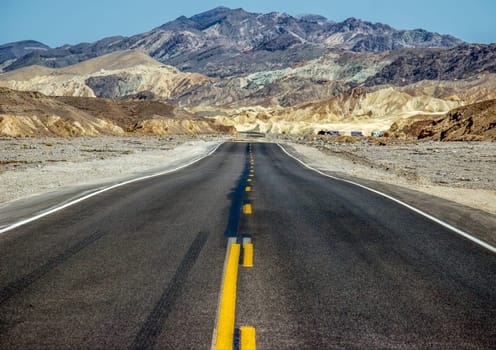 road in the desert valley with mountains in background