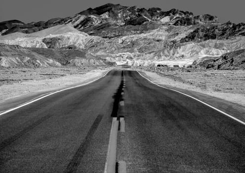 road in the desert valley with mountains in background