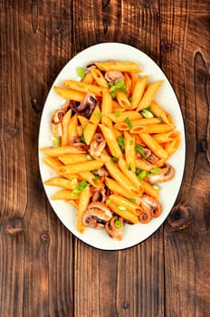 Tasty macaroni or pasta boiled with octopus. Macaroni with seafood on old rustic wooden table.