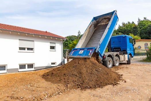 unloading the truck with potting soil from the truck bed at the construction site in Germany