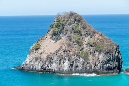 Fernando de Noronha, Brazil. View of single rock of Morro dos Dois Irmaos with crystal clear turquoise ocean