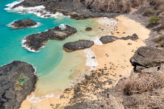 Fernando de Noronha, Brazil. View of scenic empty beach with rock at Parque Nacional Marinho.