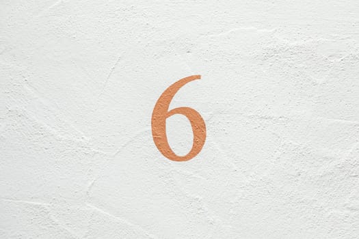 house number 6 at a harmonic white painted wall