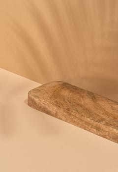 Wooden platform, shadow from a palm leaf on a brown background. Place for displaying cosmetics