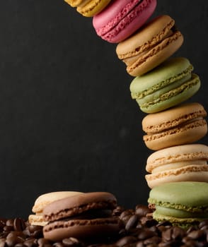 Stack of multi-colored macarons on a background of coffee beans, black background