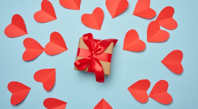 Gift box with red satin ribbon and bow on a blue background.Holiday background with Birthday or Christmas present, flat lay