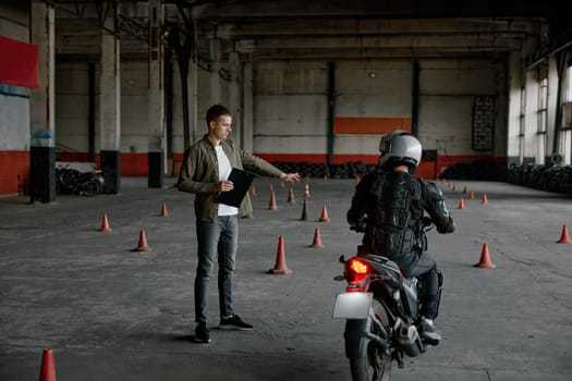 Personal lesson at motorcycle school. Male instructor teaching young biker explaining important things before start to move