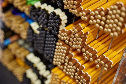 Various wooden pencils on rack display for sale in stationery shop. School or office supplies for drawing, writing or sketching. Selective focus