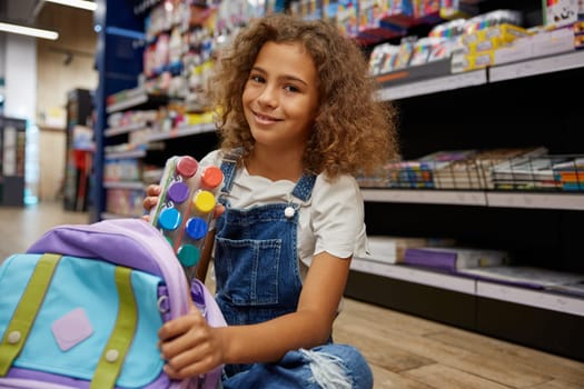 Smart girl putting paints kit into schoolbag. Shopping before back to school, preparation for education at arts lesson
