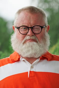 Sad and frustrated senior man with eye glasses and full beard looking at camera.