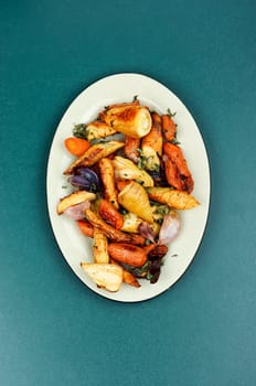 Healthy homemade roasted parsnip root, carrots and garlic on rustic wooden table.