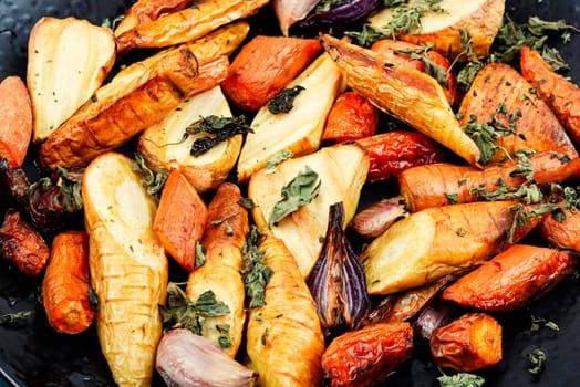 Healthy homemade roasted parsnip root, carrots and garlic on rustic wooden table.
