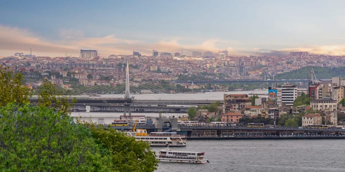 Panoramic skyline of European side of Istanbul with ferry boats sailing in Bosphorus strait, overlooking Halic Metro Bridge with clear sky in a spring day before sunset, Istanbul, Turkey