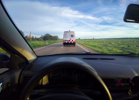 Driving behind an ambulance on local road. View from the inside of the car. View from the inside of the car