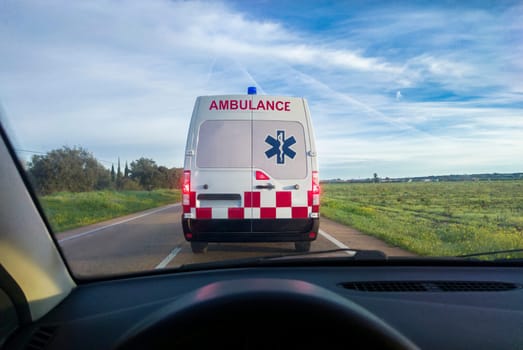 Driving behind an ambulance on local road. View from the inside of the car. View from the inside of the car