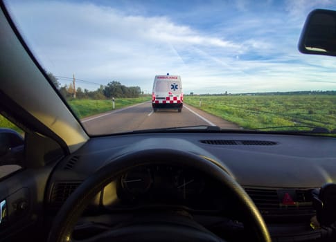 Driving behind an ambulance on local road. View from the inside of the car. View from the inside of the car