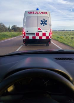 Driving behind an ambulance on local road. View from the inside of the car. View from the inside of the car
