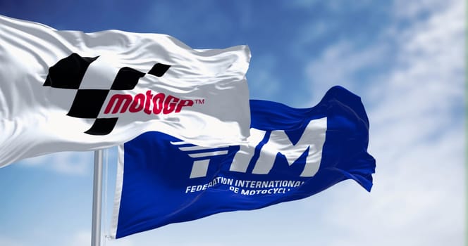 Sepang, MY, Feb. 07 2024  Flags of MotoGP and FIM waving in the wind on a clear day. Premier motorcycle racing competition. Illustrative editorial 3d illustration render