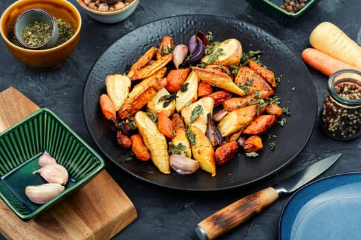 Winter garnish of baked parsnip root, carrots and garlic. Copy space.