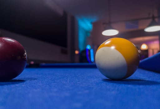 Eight-ball pool game at six pocket blue table. Yellow stripe and solid purple ball
