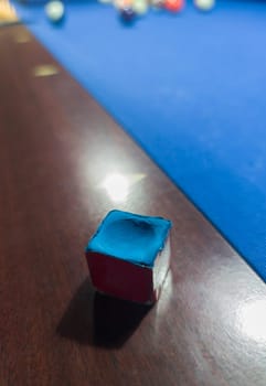Used chalk cube placed over rail. Eight-ball pool game at six pocket blue table
