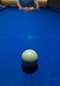 Player racking the balls. Eight-ball pool game at six pocket blue table