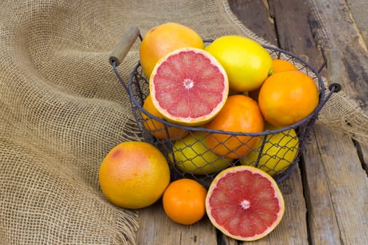 citrus fruits in a basket on wooden background