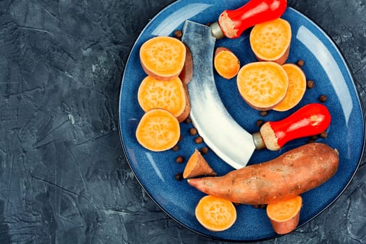 Raw sweet potatoes or batatas. Yam on concrete kitchen table. Dietary food. Space for text.