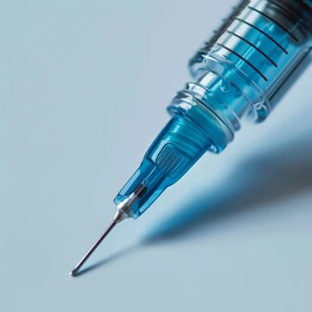 Close-up of a blue syringe with a sharp needle, isolated on a light background