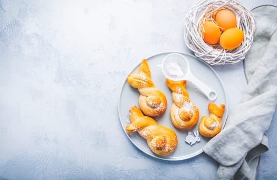 Buns made from yeast dough in a shape of Easter bunny and colored eggs