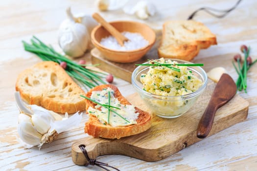 Homemade garlic butter with chives and fresh roasted baguette with salt