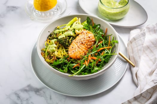 Grilled salmon fillet with parmesan broccoli and fresh vegetable salad, avocado dressing. Mediterranean diet.