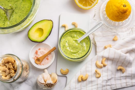Homemade avocado yogurt dressing with ingredients on kitchen table